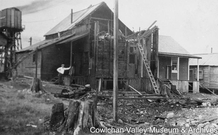 [Unidentified man standing next to damaged building]